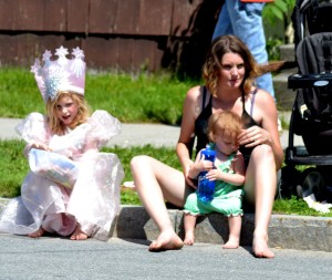 Kelsey Baughan (left), 6, came from her North Syracuse home dressed as Glinda to watch Saturday's Oz-Stravaganza parade in Chittenango. She sat with her mother, Kristen Baughan; and her younger sister, Keri, 14 months. Photo by Brian McDowell
